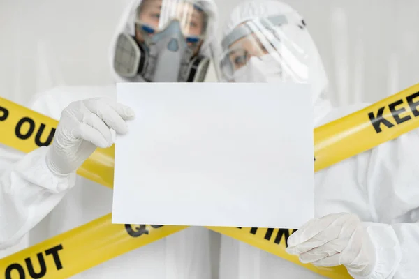 Médicos epidemiologistas homem e mulher estão segurando branco vazio placa em branco com lugar para imagem de texto. Linha amarela Manter Fora Quarentena — Fotografia de Stock