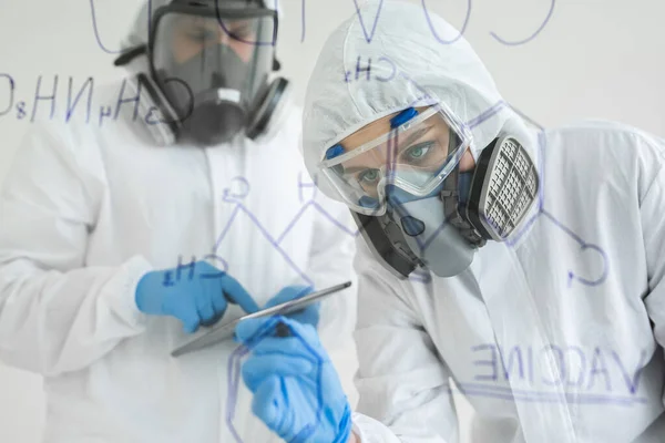 실험실의 여성 과학자들은 화학식을 작성 한다. Covid-19 의 개념 — 스톡 사진