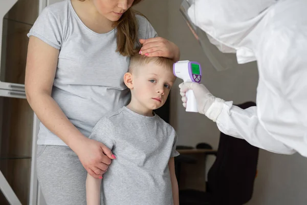 소아과 의사나 의사는 바이러스 의증상 이 유행하는 코로나 바이러스 유행 개념에 대한 적외선 이마 온도계를 사용하여 소년들의 체온을 검사한다 — 스톡 사진