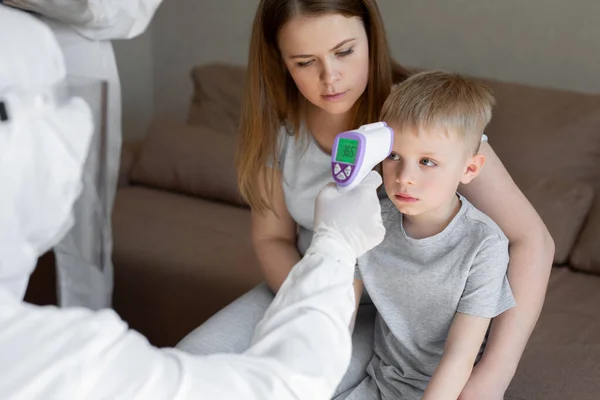 코로나 바이러스. 의사는 소년들의 체온을 적외선 이마 온도계를 사용하여 바이러스와 일치하는 19 번의 증상 - 유행성 전염병 발병 개념을 검사한다. 고온. — 스톡 사진
