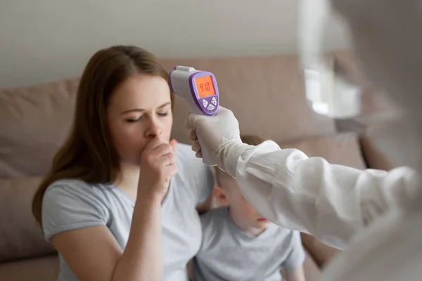 Doctor check patient body temperature using infrared forehead thermometer gun at home. Coronavirus, covid-19, high fever and cough