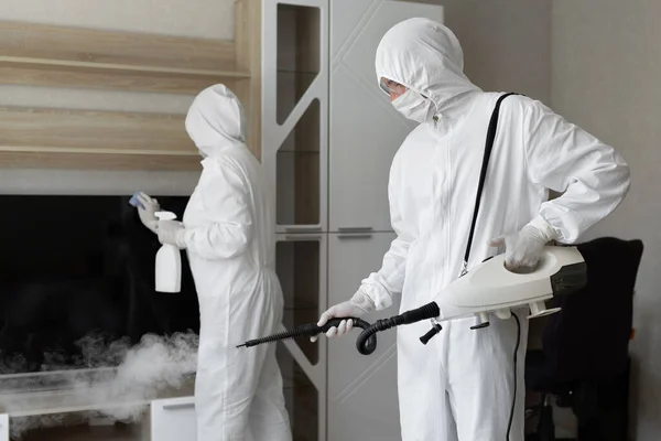 Coronavirus dezenfeksiyonu. Tehlikeli maddeler kullanan insanlar dezenfekte yapıyor. Fotokopi odası, sıcak buhar temizleme.