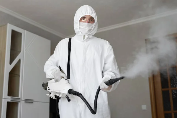 Désinfecteur en combinaison de protection effectue la désinfection à la maison. désinfection professionnelle contre COVID-19, coronavirus. dans les vêtements de protection contre l'empoisonnement chimique dans l'industrie — Photo