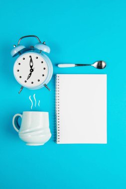 Kahve fincanı ve mavi arka planda boş bir defter.