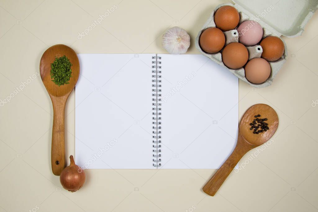 Wooden ladles with some herbs and food spicesm eggs and blank notebook