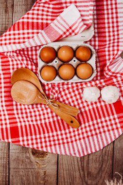 Tahta kepçe, sarımsak ve yumurta kırmızı ve beyaz bir masa halısı üzerinde.