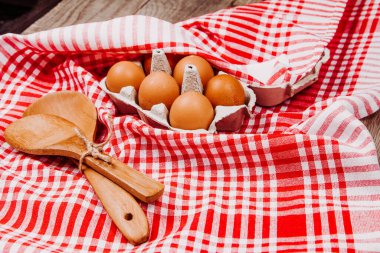 Tahta kepçe, sarımsak ve yumurta kırmızı ve beyaz bir masa halısı üzerinde.