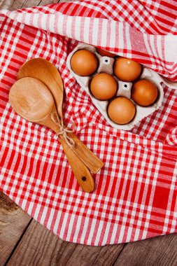 Tahta kepçe, sarımsak ve yumurta kırmızı ve beyaz bir masa halısı üzerinde.