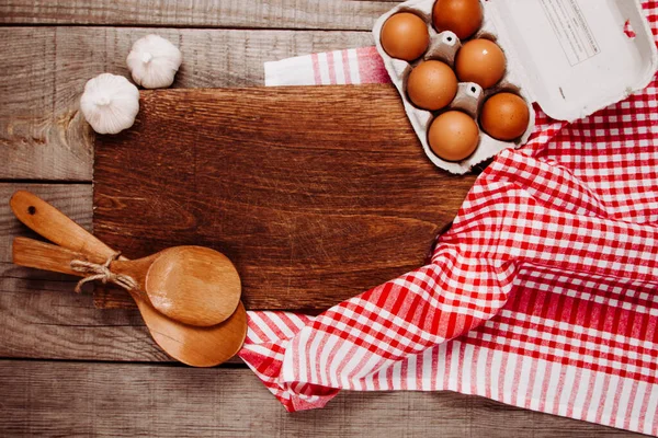 Tahta kesme tahtası, ahşap arka planda sarımsak, kepçe ve yumurta ile.