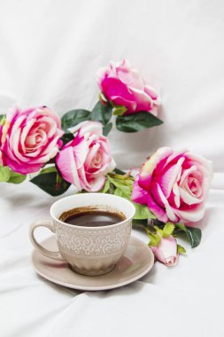 Beyaz çarşafta pembe güllerle sade kahve.