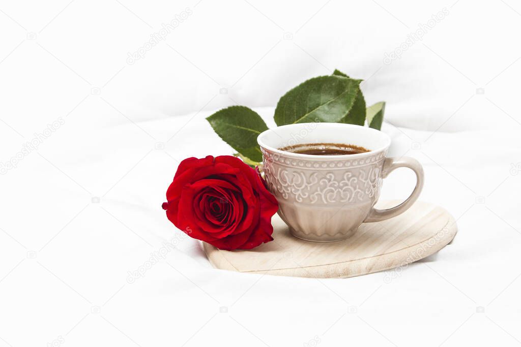 Black coffee with red rose on a white sheet