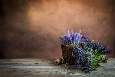 Ahşap bir masanın üzerinde güzel lavanta çiçeklerinin eski bir fotoğrafı.