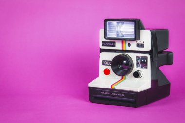 Canlı pembe arka planda Polaroid fotoğraf makinesi