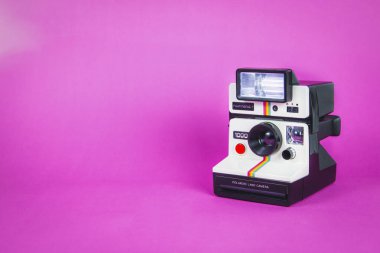 Canlı pembe arka planda Polaroid fotoğraf makinesi