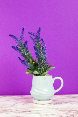 Lavanta çiçekleri mavi bir kupada mermer bir masada ve mor bir arka planda