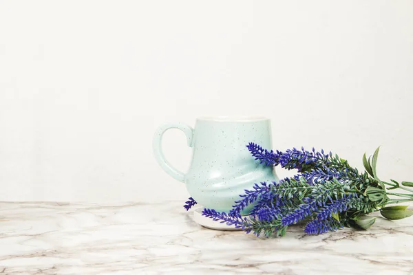 Lavender flowers and pastel blue mug on a marble table