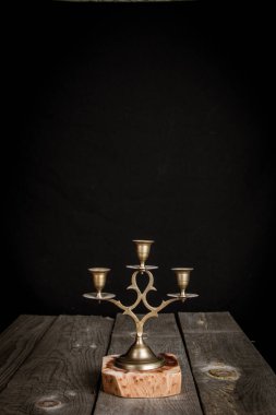 Ahşap bir masanın üzerinde siyah arka planı olan taşralı bir şamdan.