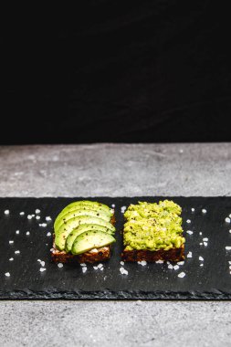  Kahvaltıda siyah tabakta sağlıklı avokado tostu. 