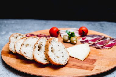 Ahşap tabakta kahvaltı için et ve küçük ekmek.