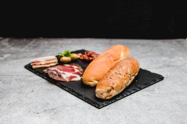 Ahşap tabakta kahvaltı için et ve küçük ekmek.