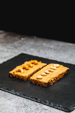Fıstık ezmesi, siyah tabakta sağlıklı bir ekmek.
