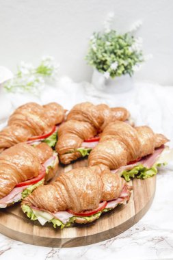 Tahta bir masa ve mermer bir yüzey üzerinde sandviç kruvasanı.