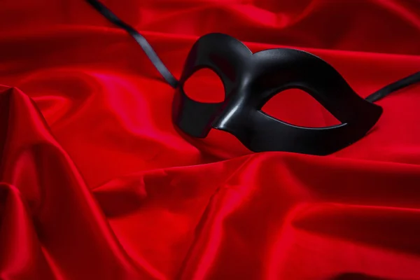 Sexy black mask on a red silk background