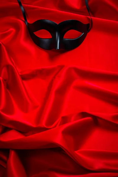 Sexy black mask on a red silk background