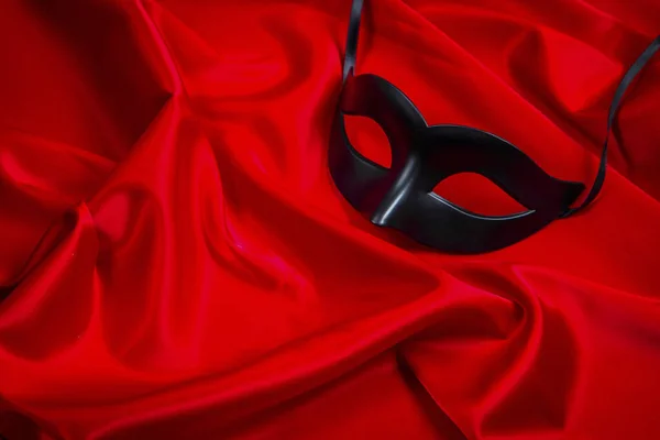 Sexy black mask on a red silk background