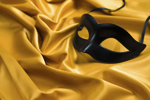Sexy black mask on a yellow silk background
