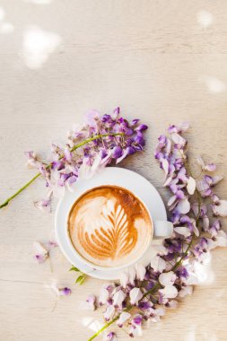 Etrafı güzel bahar çiçekleriyle çevrili kahve kapuçinosu.