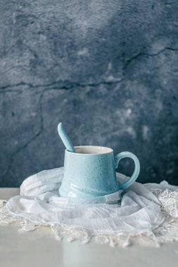 Pastel mavi kahve fincanı. Beyaz eşarpla sarılmış. Kırsal masa ve homurdanma arkaplanı.