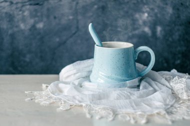 Pastel mavi kahve fincanı. Beyaz eşarpla sarılmış. Kırsal masa ve homurdanma arkaplanı.