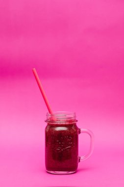 Sağlıklı koyu kırmızı smoothie pembe arka planda cam bir kavanozda