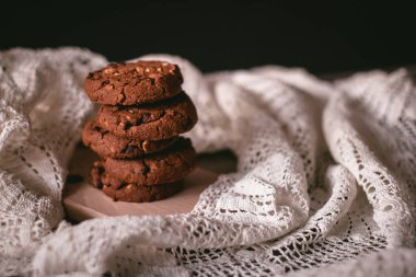 Dantel ve ahşap masada ev yapımı çikolatalı kurabiyeler.