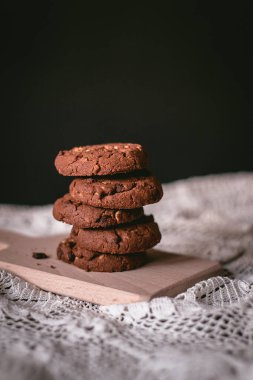Dantel ve ahşap masada ev yapımı çikolatalı kurabiyeler.
