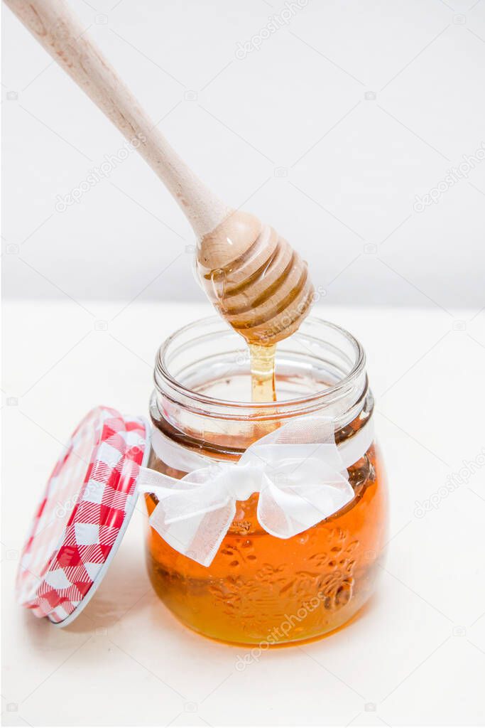 Photo of a honey jar and a honey spoon on a white background from the above