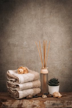 Kaplıca malzemeleri, aroma çubukları, taşlar, havlular, ahşap bir arka planda deniz kabuğu.