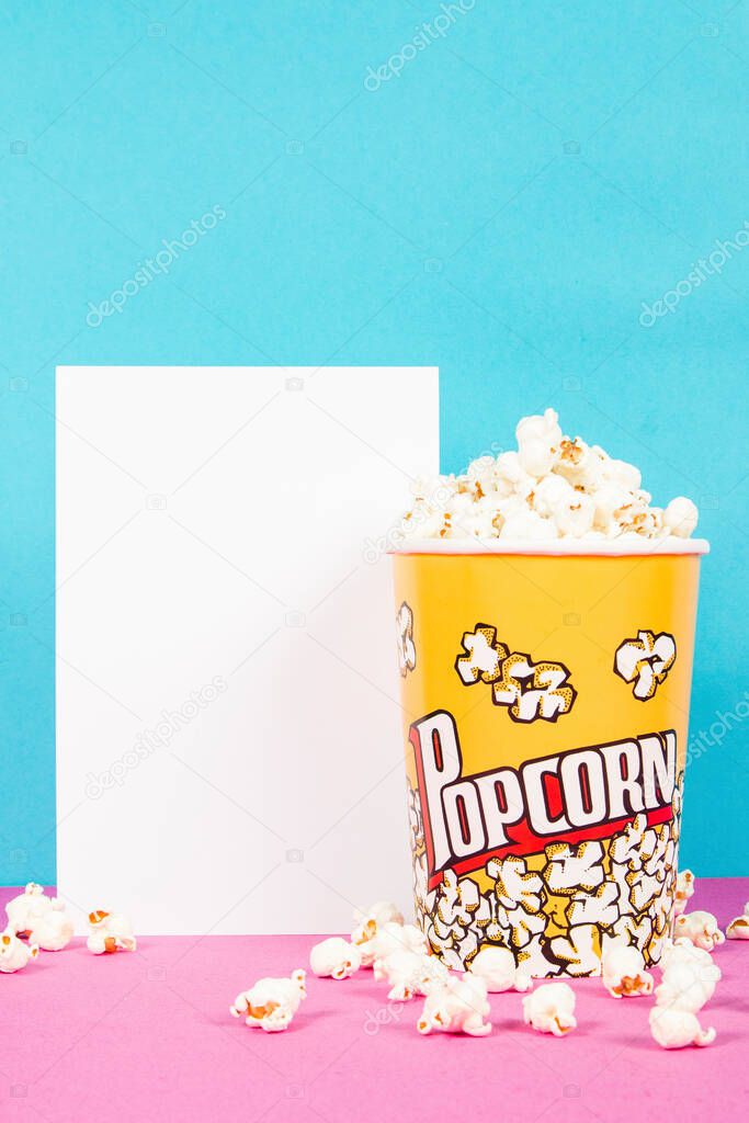 Yellow box of fresh popcorns on a pink and blue background