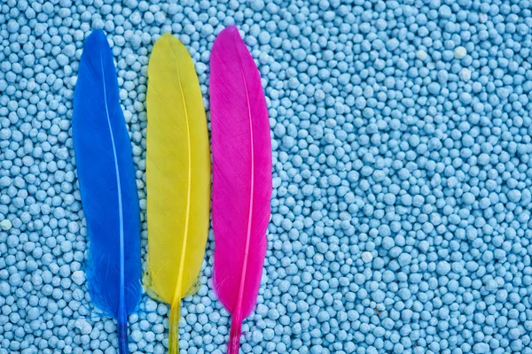 blue, yellow  and  red  feather on blue chemical fertilizers background.