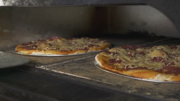 Jemand holt Pizza mit Spezialschaufel aus dem Ofen — Stockvideo
