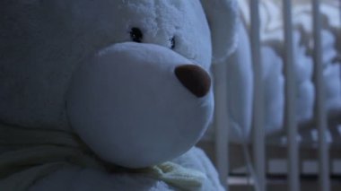 Arka plan üzerinde Bebek karyolası/beşik tarafından closeup oyuncak ayı oturur