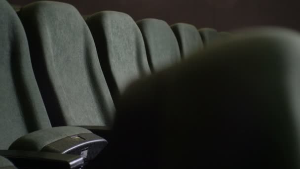 Feche uma fileira de cadeira cinza vazia no salão de cinema escuro — Vídeo de Stock