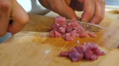 Makro pişirme elleri profesyonel olarak bıçakla kesilmiş mutfak masasındaki tahta tahtada küp şeklinde.