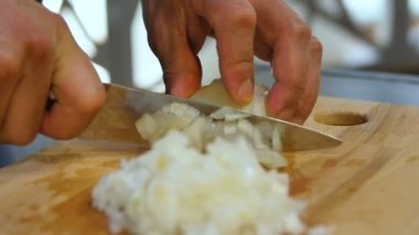 Makro aşçı elleri mutfak masasındaki bıçakla günışığına karşı profesyonel soğan doğruyor.