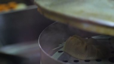 Makro kişi, Tatar köfteli köfte ile buhar kazanının üstündeki kapağı açıyor.