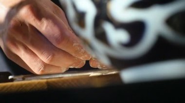 Makro eller, parlak gün ışığına karşı süslü mavi ve beyaz kâselerde tahta tahtanın üzerindeki parmaklarla hamur çemberleri oluşturur.