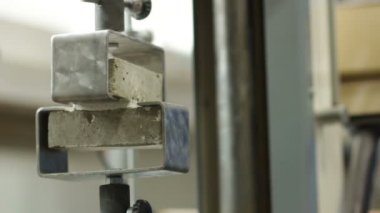 Kadın operatör çimento karışımının dayanıklılığı ve dayanıklılığı üzerinde laboratuvar testleri yürütüyor.