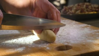 Parlak gün ışığına karşı un kaplı tahta tahtanın üzerinde merdane hamuru şeklinde kesilmiş eller.