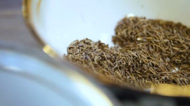 Makro pişirme parmakları, baharatlı otları mutfak masasındaki parlak arka planda kaseye döker.